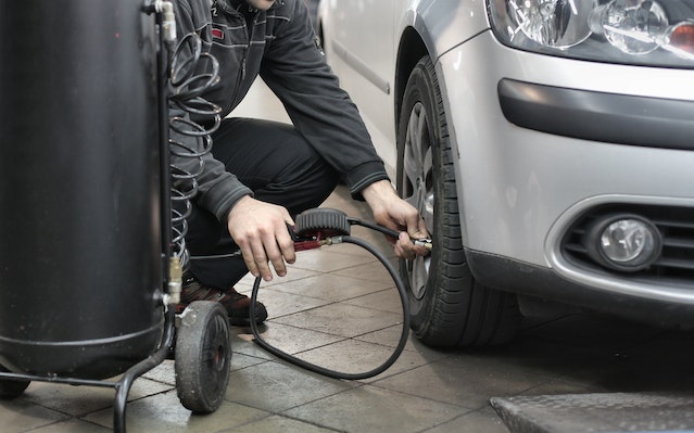 hombre hinchando una rueda de coche
